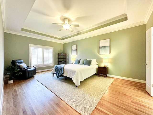 bedroom featuring a raised ceiling, crown molding, ceiling fan, and light hardwood / wood-style floors