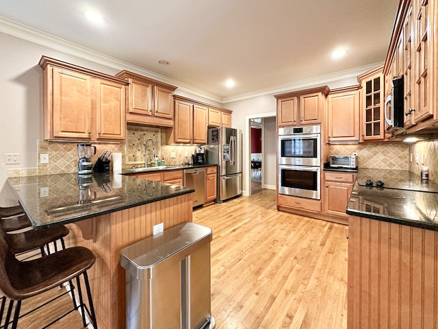 kitchen featuring appliances with stainless steel finishes, backsplash, light hardwood / wood-style flooring, and kitchen peninsula