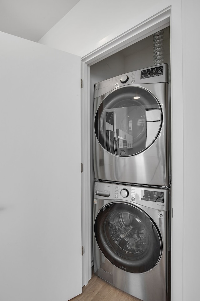 laundry room with light hardwood / wood-style flooring and stacked washer / drying machine