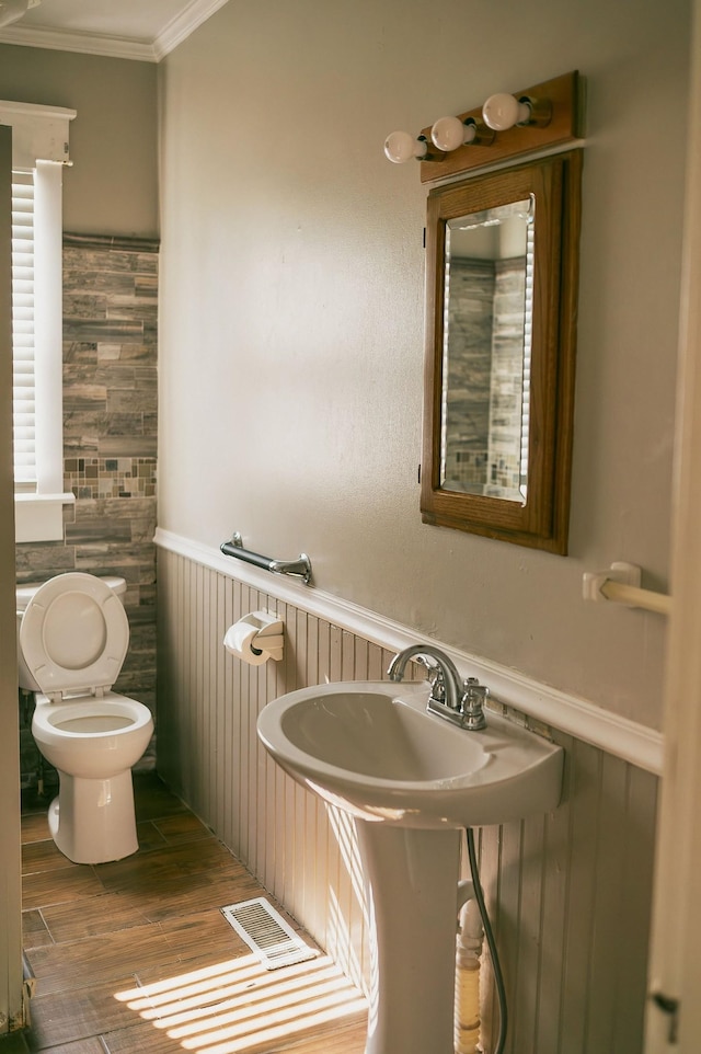 bathroom featuring hardwood / wood-style flooring, crown molding, and toilet