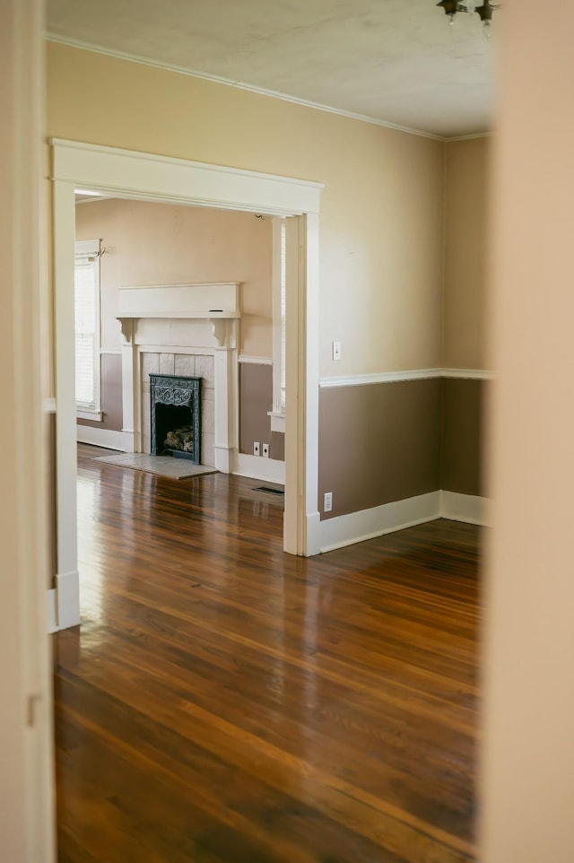 unfurnished living room featuring dark hardwood / wood-style flooring, crown molding, and a fireplace