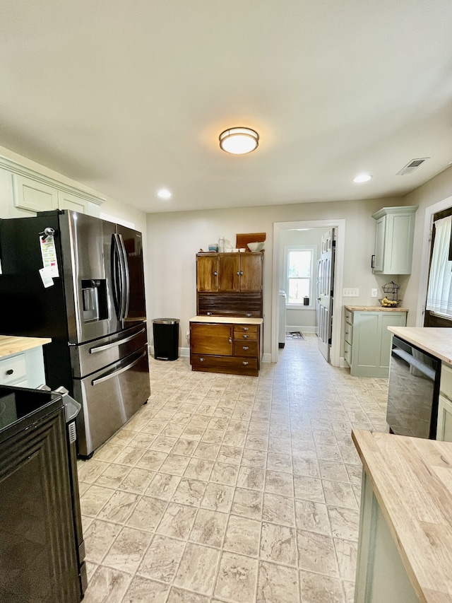 kitchen featuring light tile patterned flooring, stainless steel appliances, and butcher block counters