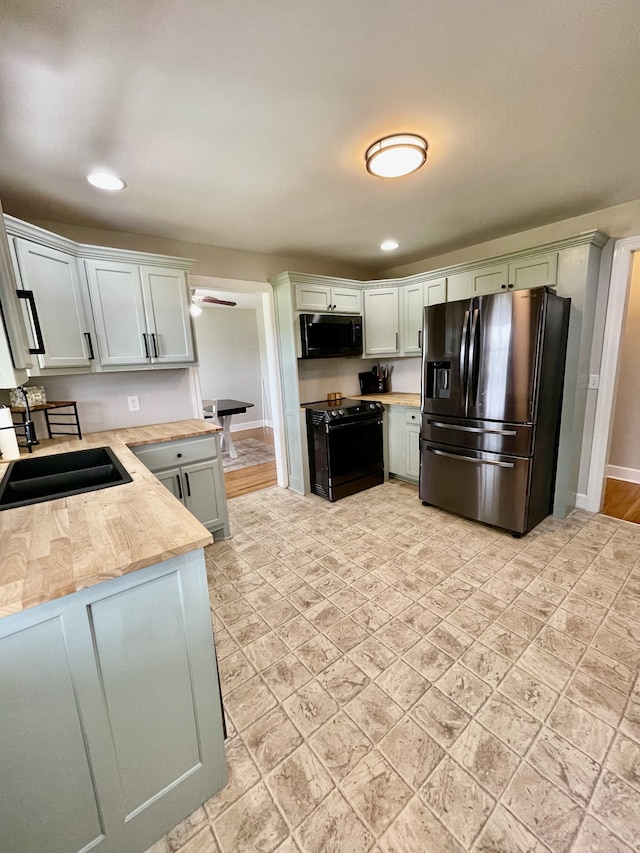 kitchen featuring black appliances, light hardwood / wood-style flooring, sink, and light stone countertops