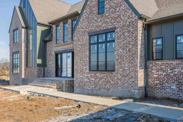 view of home's exterior with a shingled roof and brick siding