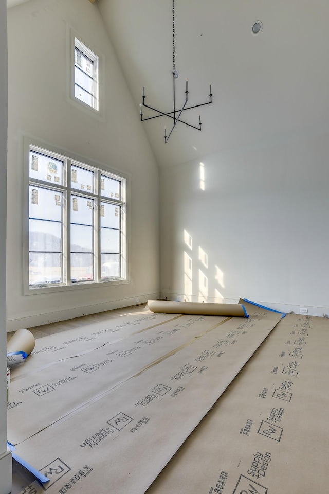 spare room with high vaulted ceiling and an inviting chandelier