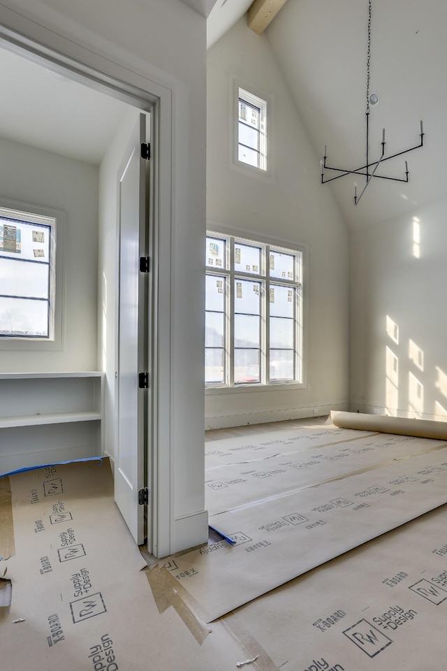 interior space featuring beamed ceiling, an inviting chandelier, and high vaulted ceiling