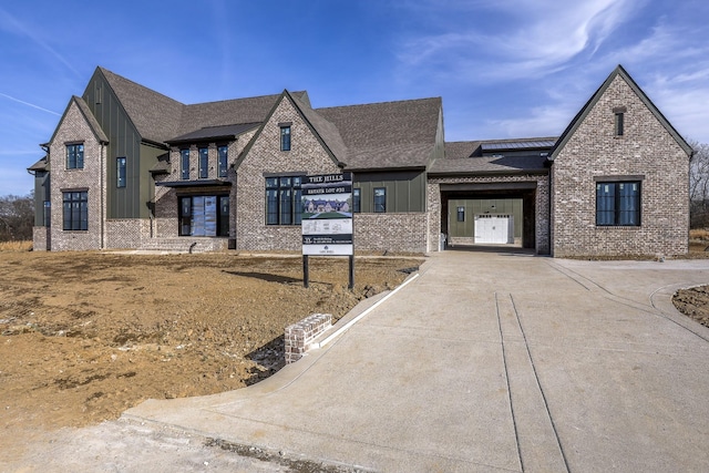 view of front of property with board and batten siding, concrete driveway, brick siding, and a garage