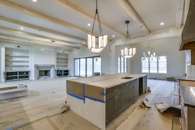 kitchen featuring open floor plan, beamed ceiling, a center island, decorative light fixtures, and a high end fireplace