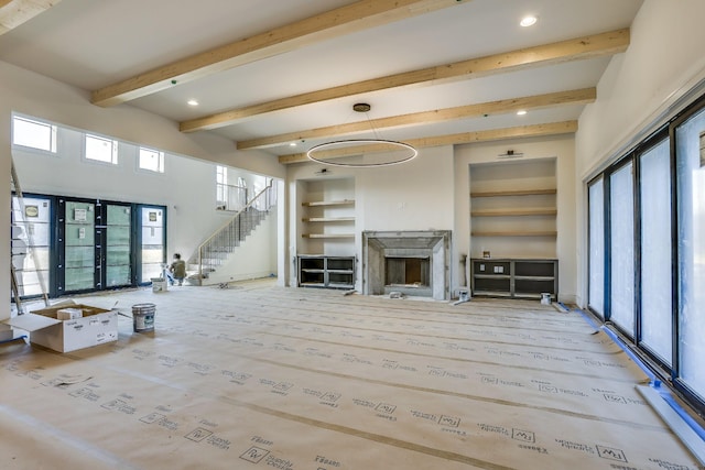 unfurnished living room featuring built in shelves, a fireplace, recessed lighting, beamed ceiling, and stairs