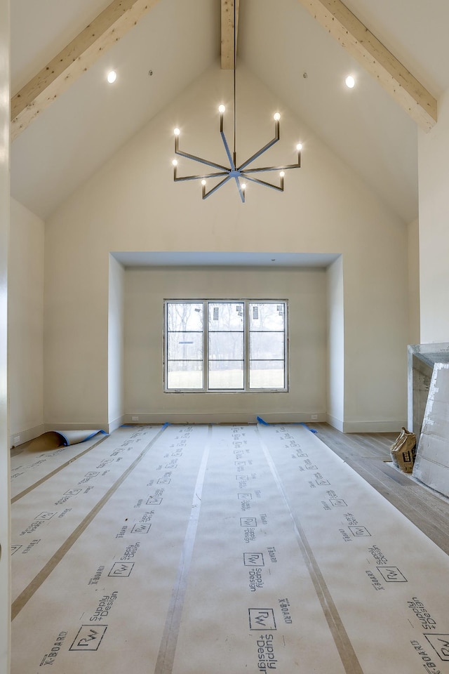 unfurnished living room with high vaulted ceiling, beam ceiling, a notable chandelier, and baseboards