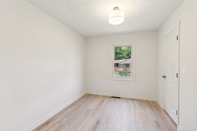 spare room featuring a textured ceiling and light hardwood / wood-style floors