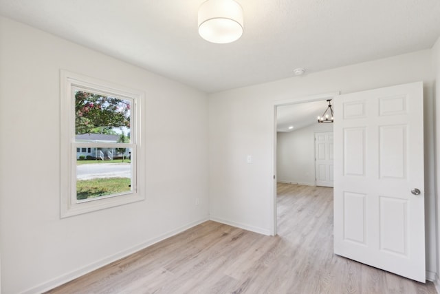 unfurnished room with a notable chandelier and light hardwood / wood-style floors