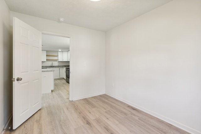 unfurnished room with sink and light hardwood / wood-style floors