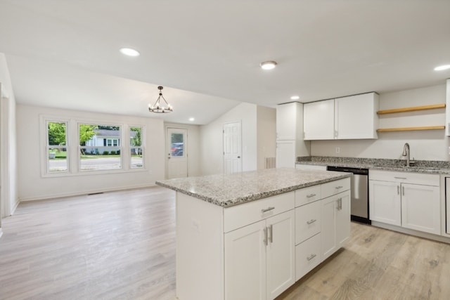 kitchen with light hardwood / wood-style flooring, stainless steel dishwasher, a kitchen island, and white cabinetry