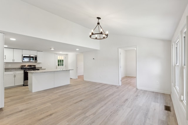 kitchen featuring white cabinets, stainless steel appliances, light hardwood / wood-style floors, and decorative light fixtures