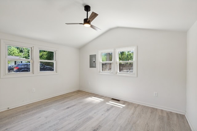 unfurnished room featuring ceiling fan, electric panel, lofted ceiling, and light hardwood / wood-style floors