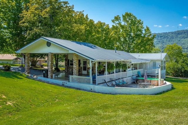 rear view of house featuring a yard, a mountain view, and a porch