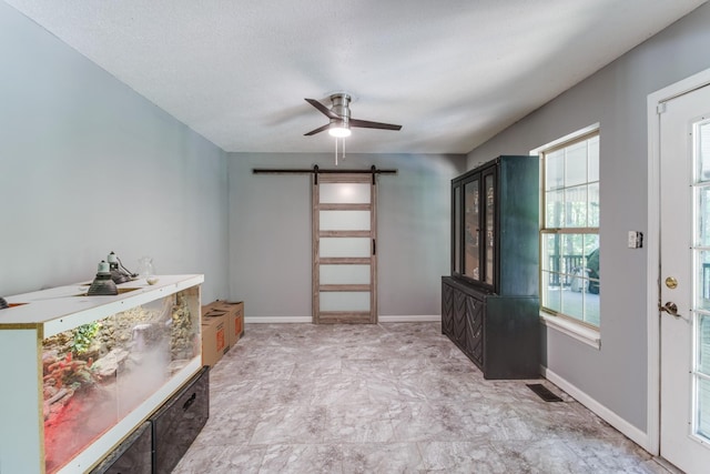 interior space featuring a barn door and ceiling fan