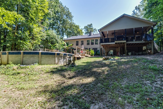 rear view of property with ceiling fan, a yard, and a sunroom