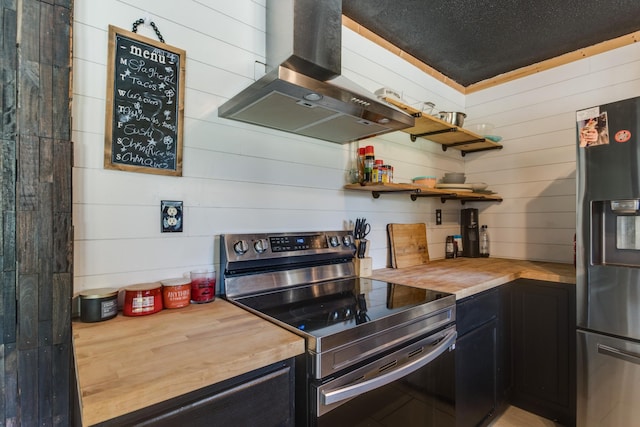 kitchen with appliances with stainless steel finishes, butcher block counters, and island range hood