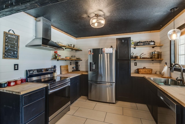 kitchen with decorative light fixtures, sink, wooden counters, exhaust hood, and stainless steel appliances