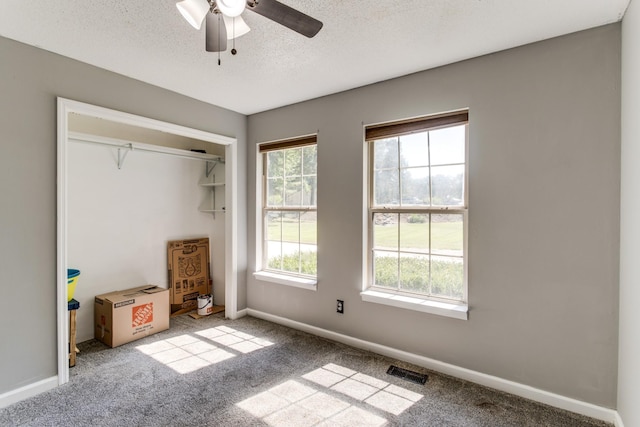 unfurnished bedroom featuring light carpet, ceiling fan, a closet, and a textured ceiling