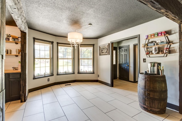 unfurnished dining area featuring light tile patterned floors, a textured ceiling, and a notable chandelier