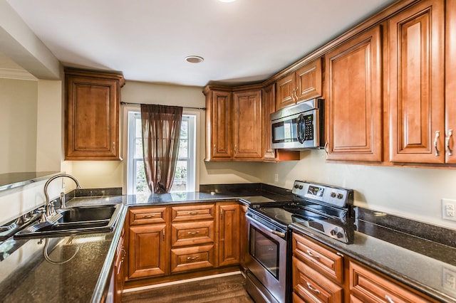 kitchen featuring appliances with stainless steel finishes, brown cabinetry, dark wood-type flooring, and a sink