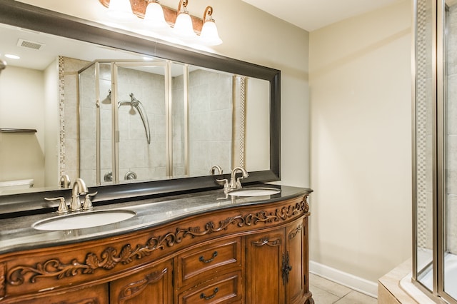 bathroom featuring a shower with shower door, double vanity, tile patterned flooring, and toilet