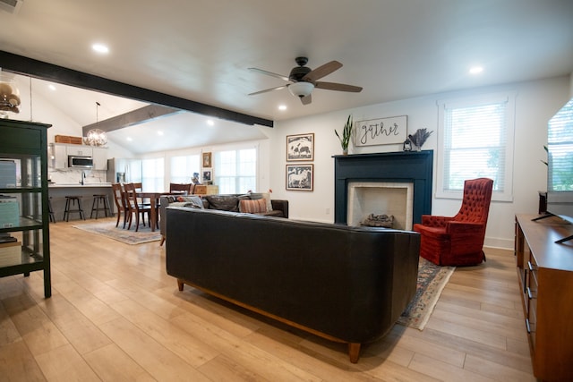 living room featuring ceiling fan with notable chandelier, vaulted ceiling with beams, and light hardwood / wood-style floors