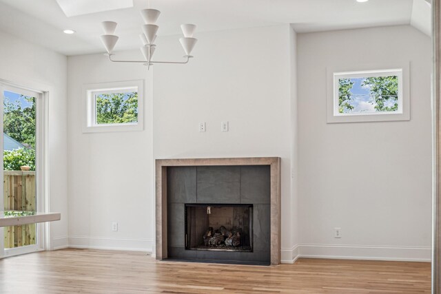 details featuring hardwood / wood-style floors, a skylight, a tiled fireplace, and an inviting chandelier