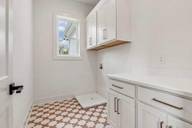 clothes washing area featuring light tile patterned floors, cabinets, and washer hookup