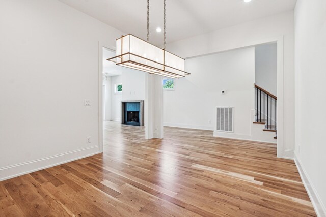 unfurnished living room featuring light hardwood / wood-style flooring, a multi sided fireplace, and a chandelier