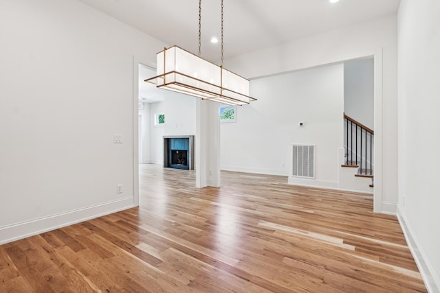 unfurnished living room with an inviting chandelier and wood-type flooring