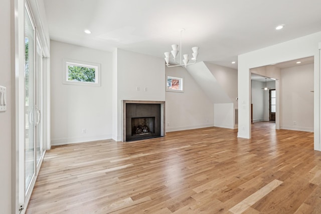 unfurnished living room featuring a tile fireplace, light hardwood / wood-style floors, and a chandelier