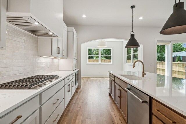 kitchen with decorative backsplash, stainless steel appliances, white cabinets, light hardwood / wood-style flooring, and sink