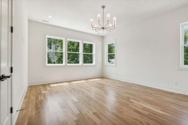 empty room with light hardwood / wood-style flooring and an inviting chandelier