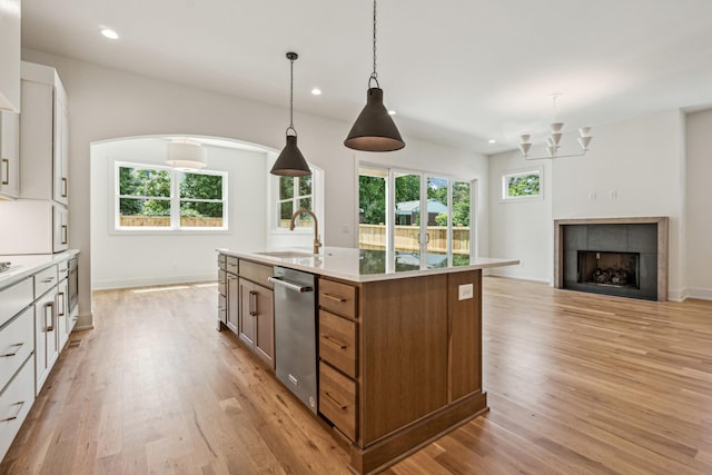 kitchen with pendant lighting, sink, light hardwood / wood-style flooring, white cabinetry, and a center island with sink