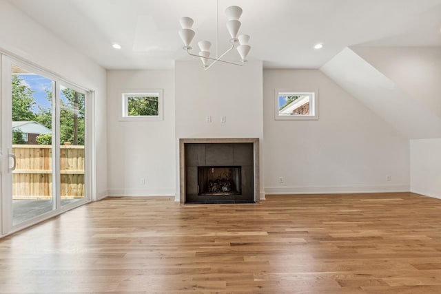 unfurnished living room with light hardwood / wood-style flooring, a fireplace, plenty of natural light, and a notable chandelier