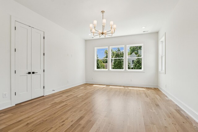 empty room featuring an inviting chandelier and light hardwood / wood-style floors