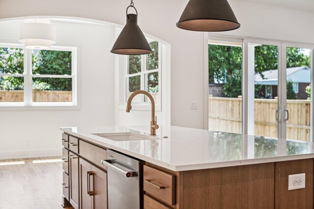 kitchen featuring stainless steel dishwasher, an island with sink, sink, and a wealth of natural light