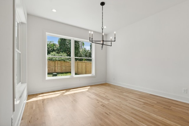 unfurnished dining area featuring a notable chandelier and light hardwood / wood-style floors