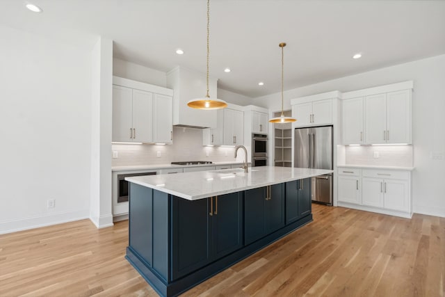 kitchen featuring light hardwood / wood-style flooring, a kitchen island with sink, hanging light fixtures, stainless steel appliances, and white cabinets