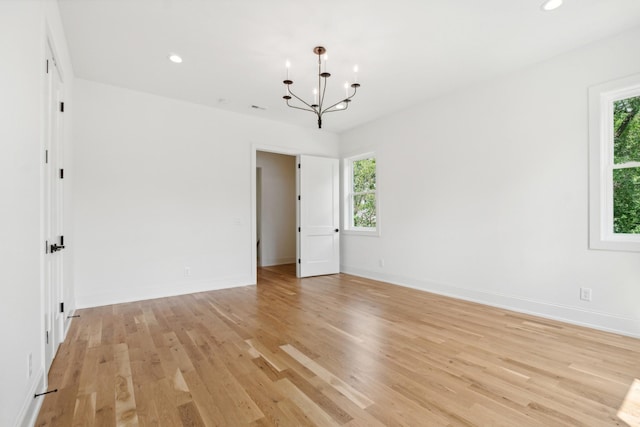 unfurnished room featuring an inviting chandelier and light hardwood / wood-style floors