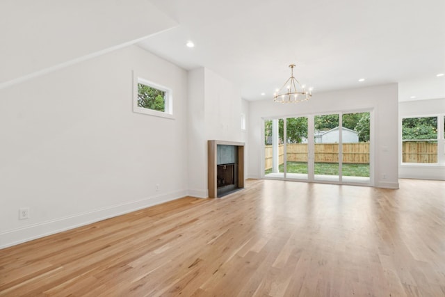 unfurnished living room featuring a notable chandelier and light hardwood / wood-style floors