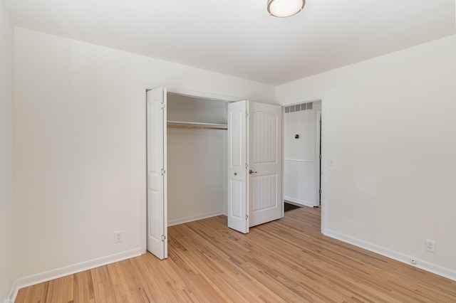 unfurnished bedroom with light wood-type flooring and a closet