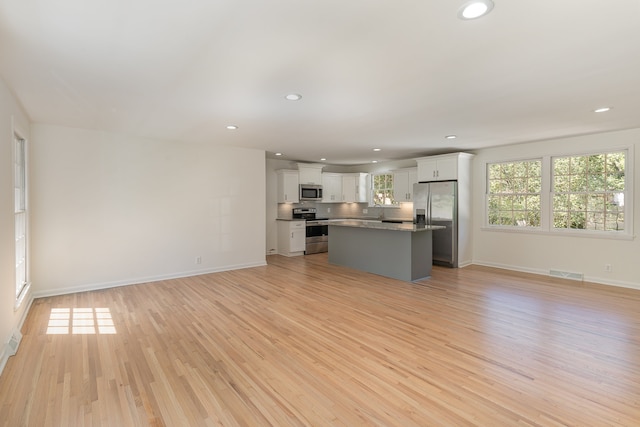 unfurnished living room with light hardwood / wood-style floors, sink, and a healthy amount of sunlight