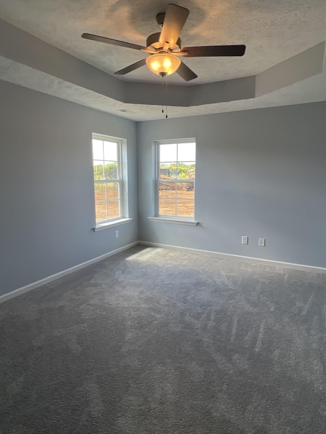 unfurnished room with a textured ceiling, a ceiling fan, baseboards, carpet, and a raised ceiling