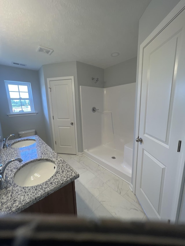 bathroom featuring marble finish floor, a shower stall, visible vents, and a sink