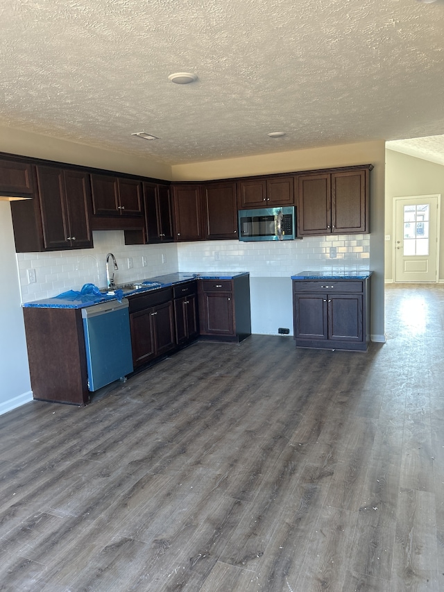 kitchen featuring stainless steel microwave, backsplash, a sink, wood finished floors, and dishwashing machine